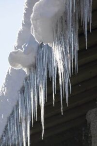 Snow covered roof ready for winter maintenance with icicles