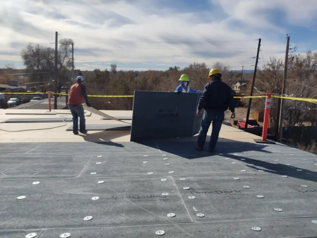 Roofing team wearing safety gear on a commercial flat roof, demonstrating compliant worksite standards for how to tell if a roofing company is legit by Elite Roofing & Solar