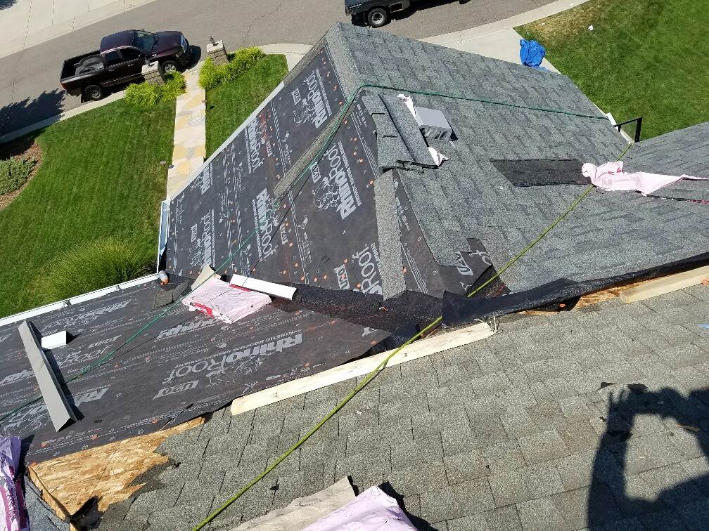 Roof replacement in progress by Elite Roofing & Solar: Workers are removing damaged shingles and installing new roofing materials in Denver, CO