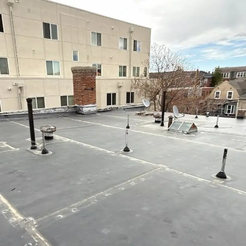 Newly installed EPDM flat roof with vent pipes and satellite dishes on a commercial building by elite-solar in Colorado