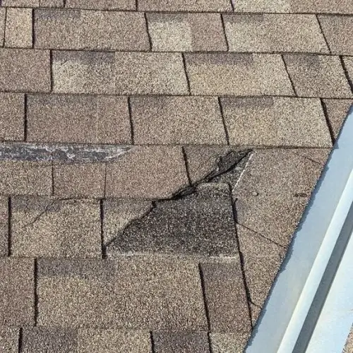 Roof edge with severe shingle cracking and visible hail impact, illustrating when to report hail damage on roof by Elite Roofing & Solar