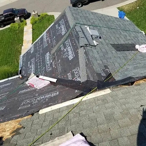 Wind damage to roof in Michigan with exposed underlayment, missing shingles, and ongoing repairs by Elite Solar in Michigan