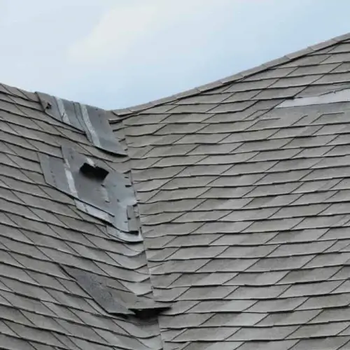 Wind damage to roof in Michigan showing missing and curled asphalt shingles exposing roof deck by Elite Solar in Michigan