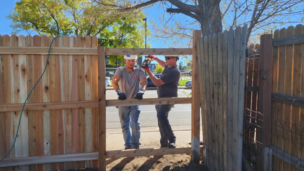 Elite Roofing & Solar team members building a wooden fence at a home as part of a charity project in Denver, CO