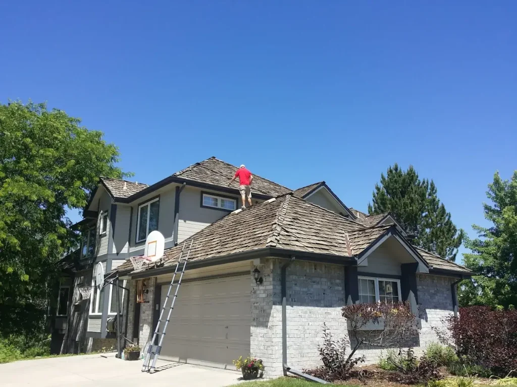 Roofing contractor Longmont inspecting home roof under clear blue sky by Elite Roofing and Solar in Longmont, CO