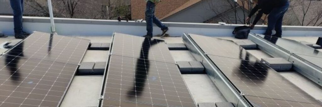 crews installing solar panels on top of a flat roof in Denver by Elite Roofing & Solar.