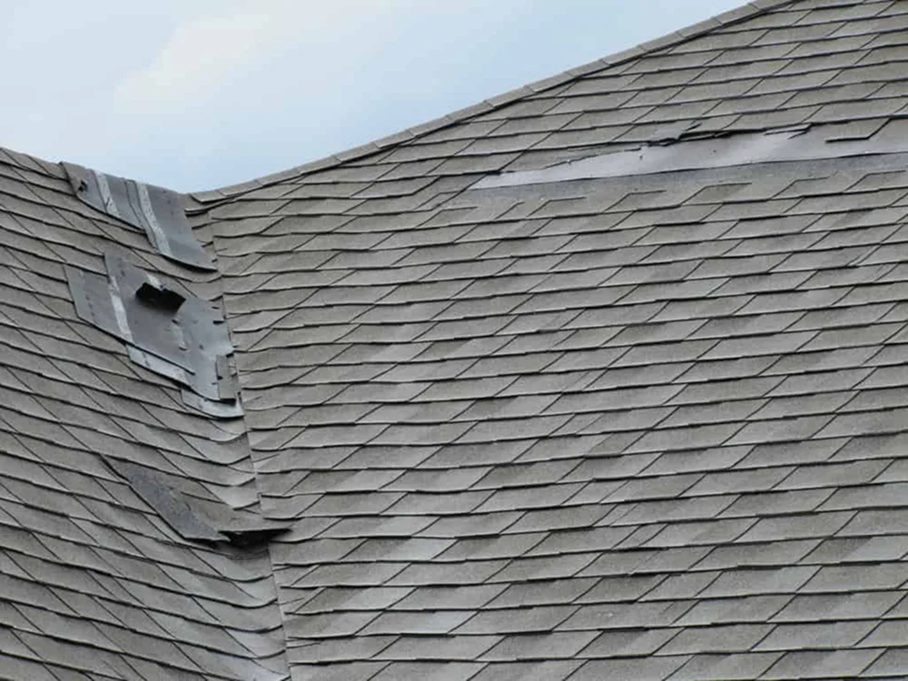 Damaged asphalt shingles on residential roof before maintenance by Elite Roofing & Solar in Denver, CO