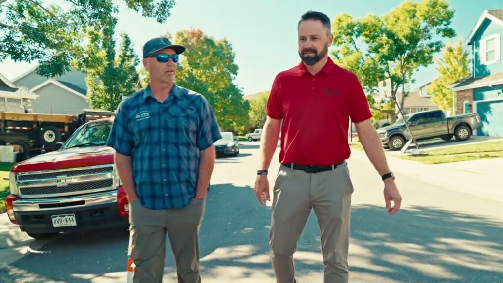Randy Brothers of Elite Roofing & Solar walking with a team member through a residential neighborhood while inspecting a roofing project in Denver, CO.