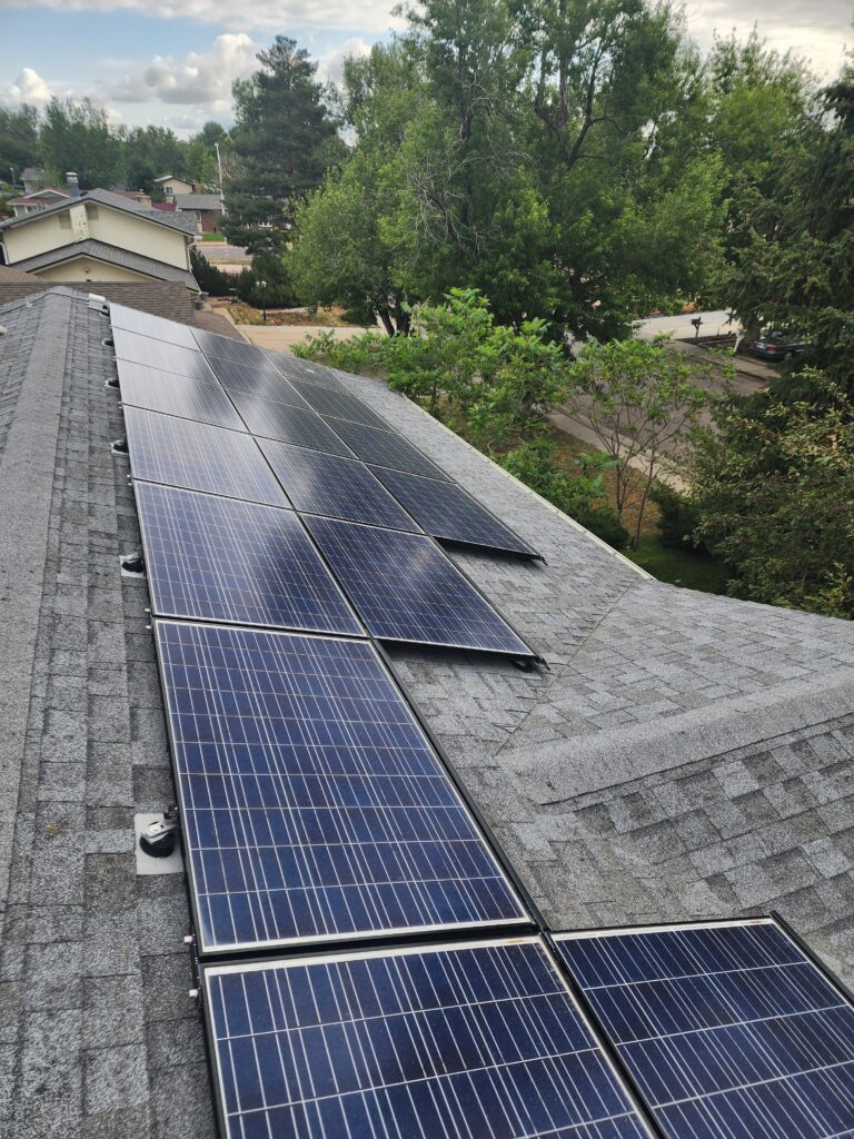 Residential rooftop with multiple solar panels installed, surrounded by trees and neighboring houses, showing a completed solar setup in Denver