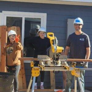 Elite Roofing & Solar team Volunteers beside a woodsaw for Habitat for Humanity community project in Denver